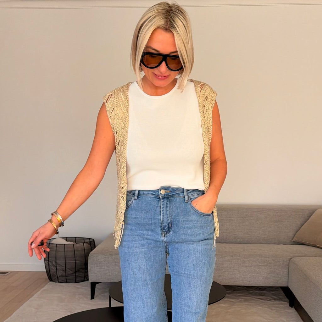 Gilet beige en maille ajourée sans manches avec franges. Léger, bohème et parfait pour un look chic et estival.