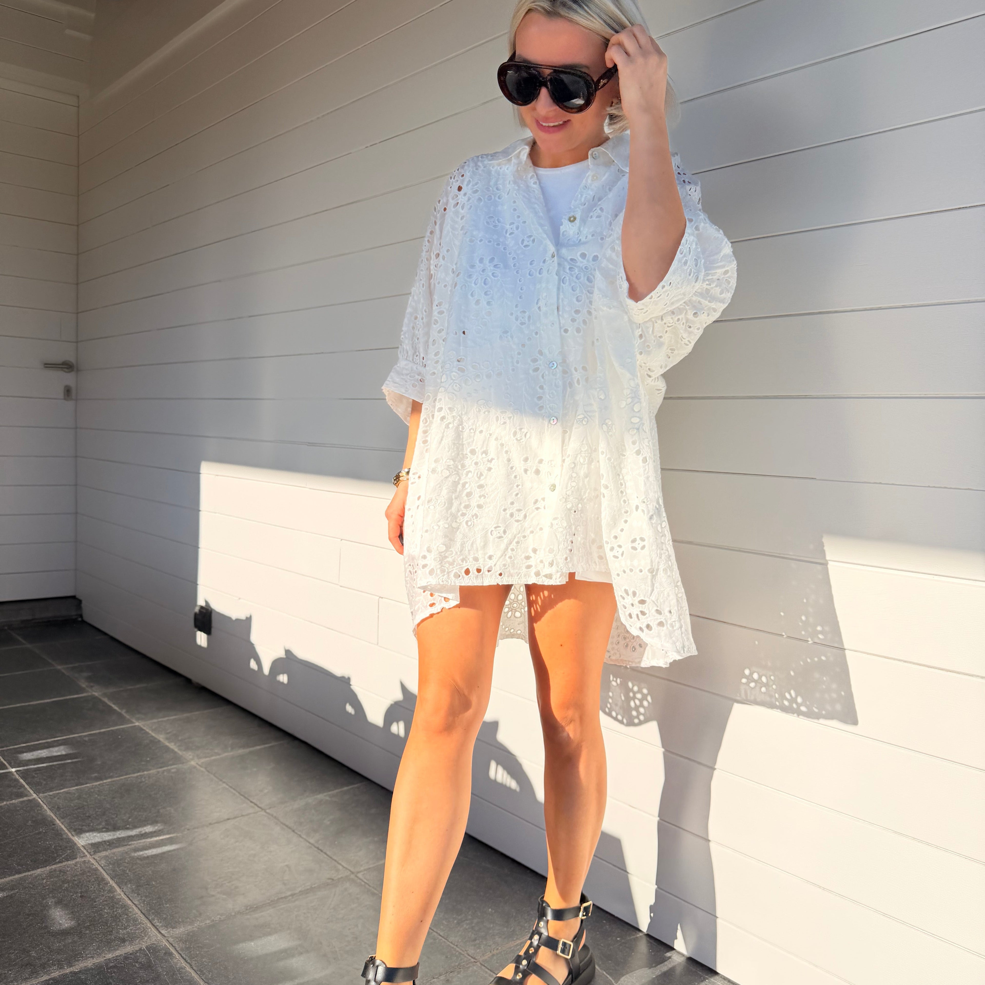 Robe chemise blanche en broderie anglaise, fluide et légère. À porter en ville ou au-dessus d’un maillot pour un look estival chic.
