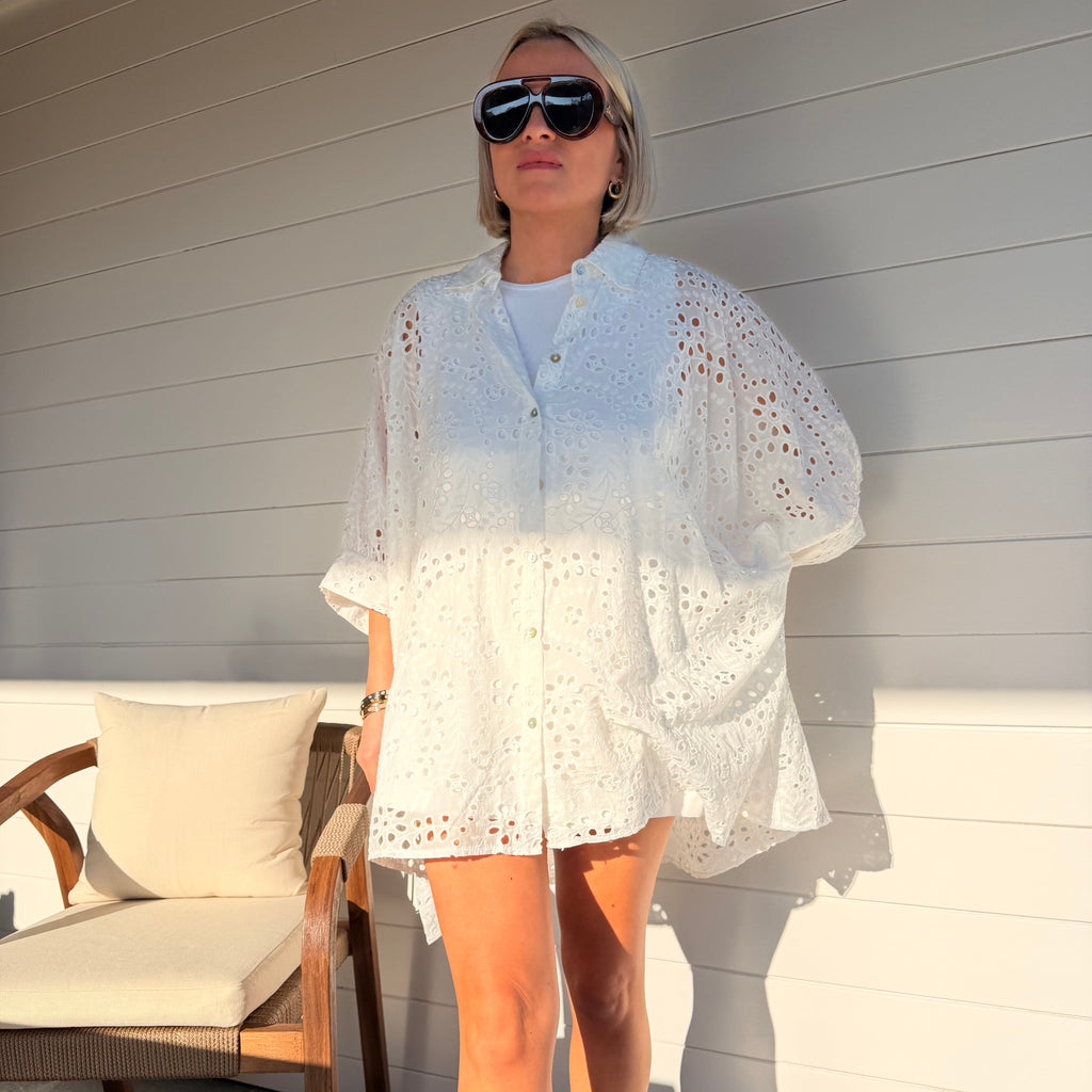 Robe chemise blanche en broderie anglaise, fluide et légère. À porter en ville ou au-dessus d’un maillot pour un look estival chic.