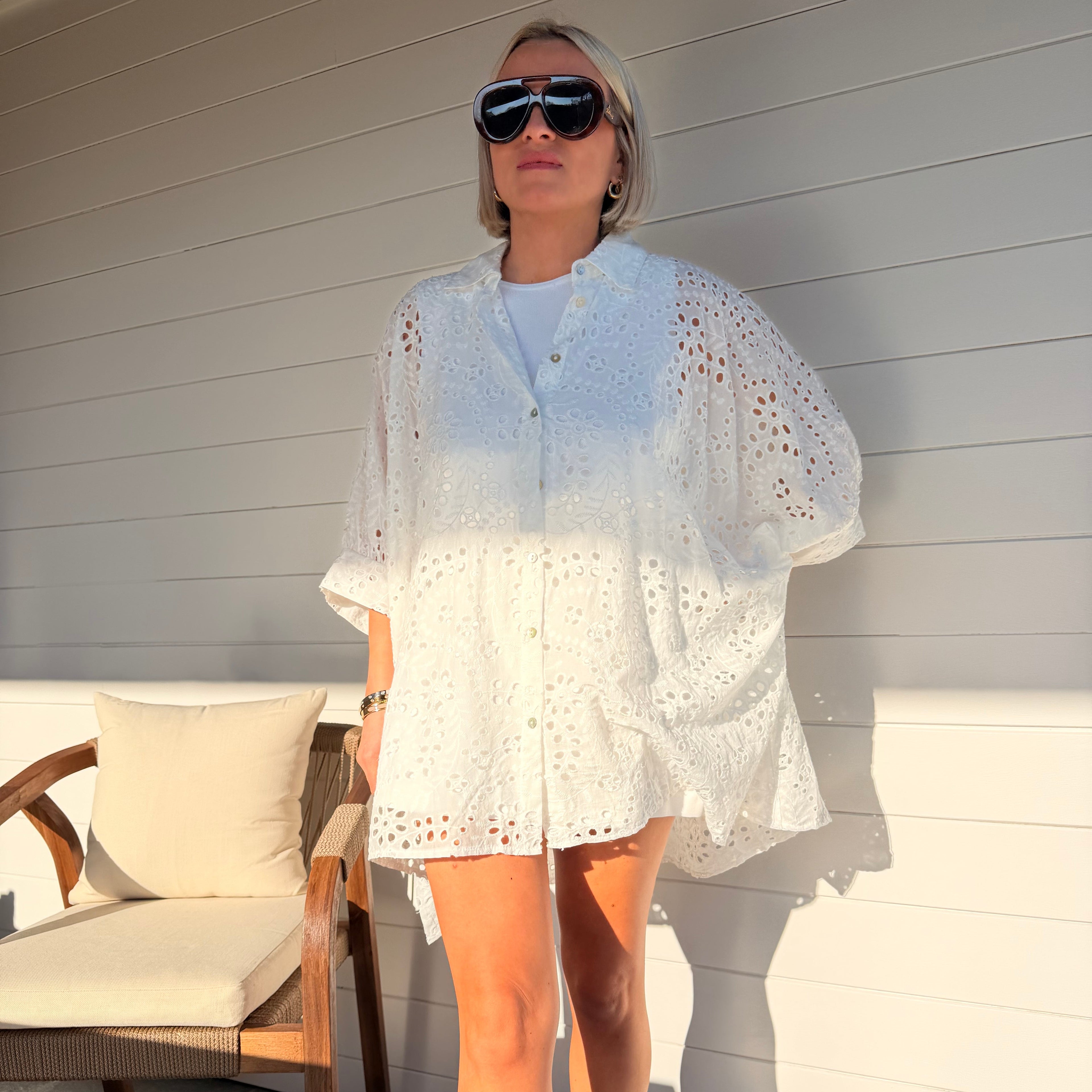 Robe chemise blanche en broderie anglaise, fluide et légère. À porter en ville ou au-dessus d’un maillot pour un look estival chic.