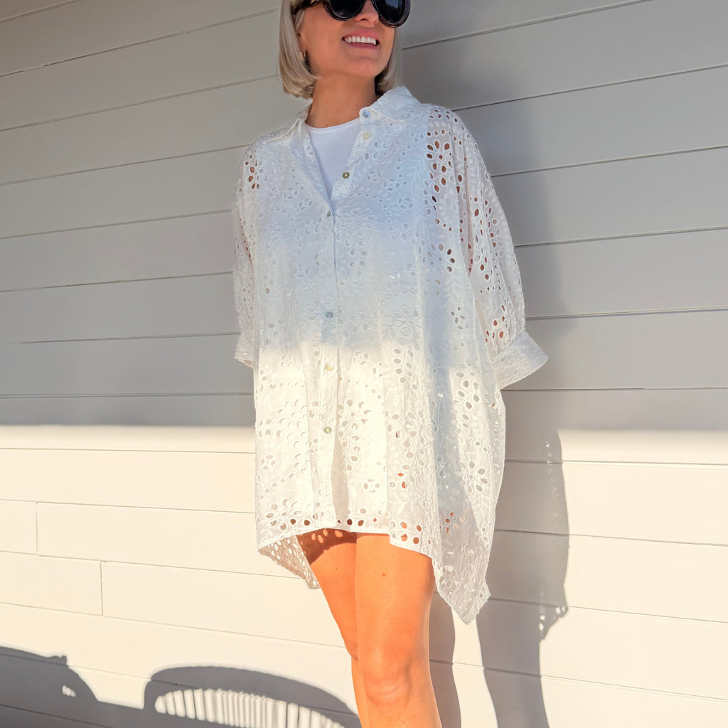 Robe chemise blanche en broderie anglaise, fluide et légère. À porter en ville ou au-dessus d’un maillot pour un look estival chic.