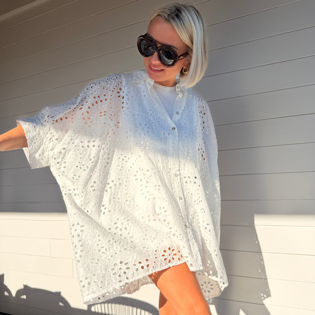 Robe chemise blanche en broderie anglaise, fluide et légère. À porter en ville ou au-dessus d’un maillot pour un look estival chic.