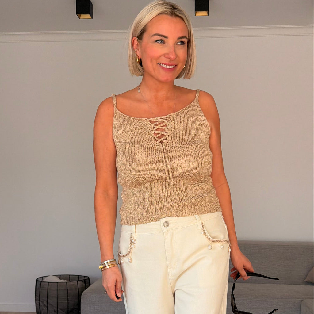 Top beige à fines bretelles avec détail lacé. Léger, féminin et parfait pour un look estival chic.